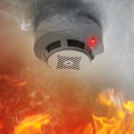 Fire alarm system detector on ceiling triggered by smoke and flame